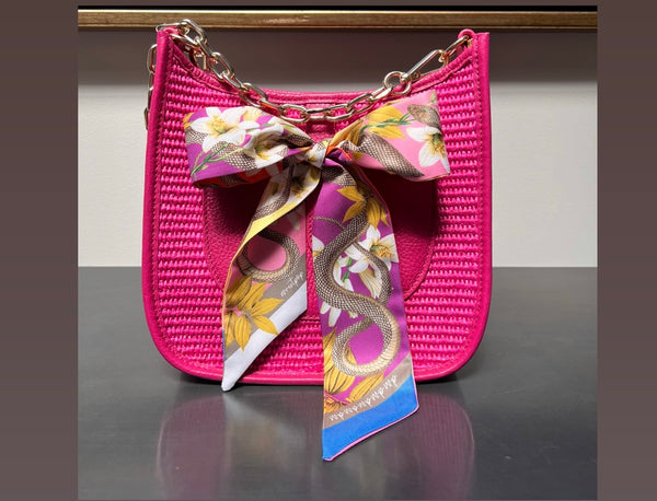 Colorful scarf elegantly tied to a stylish handbag, adding a pop of color and personality.